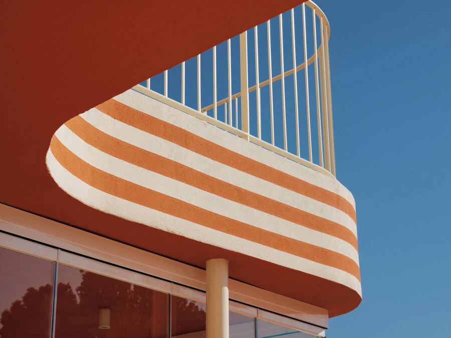 A building with a curved structure, a glass facade, and a striped awning.