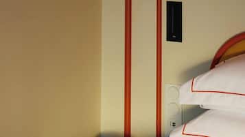 A hotel room with a bed, a bedside telephone, and a wall socket.