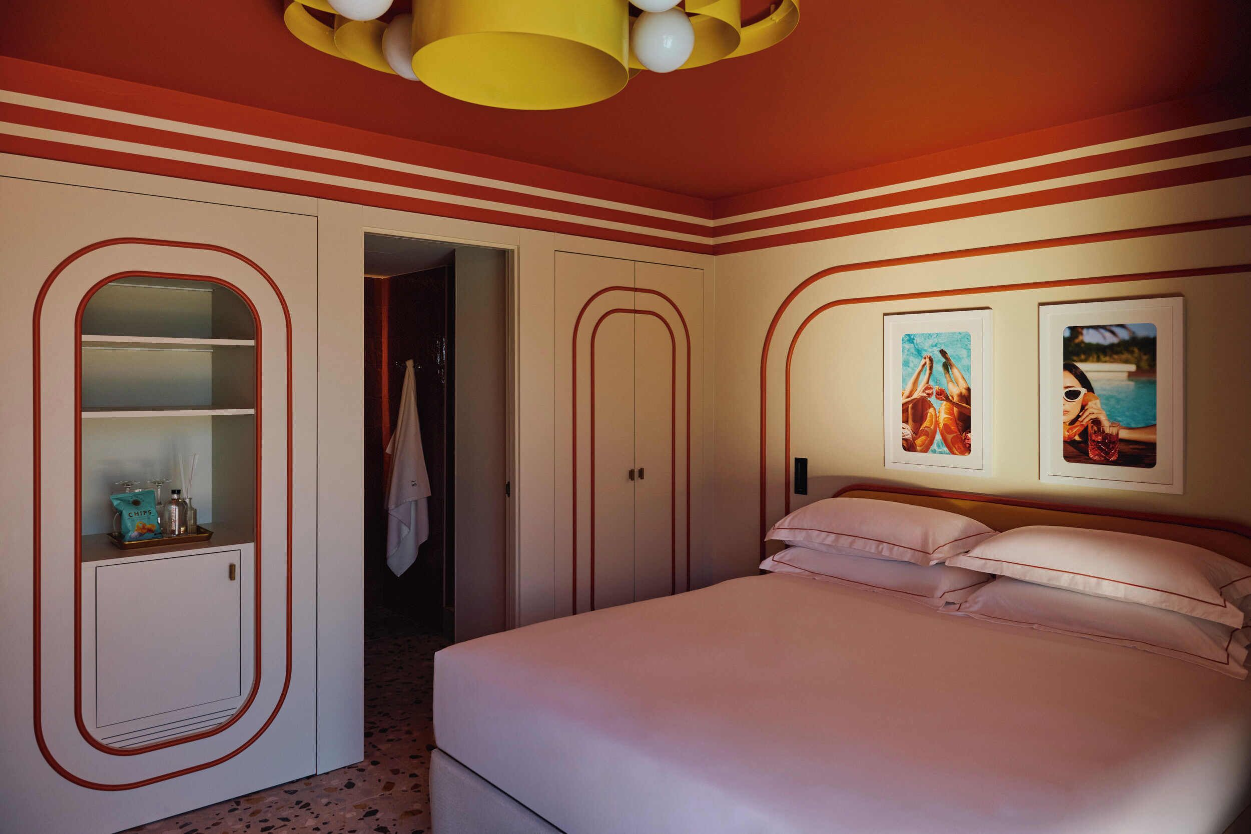 Ein Schlafzimmer mit Bett, Kleiderschrank, Spiegel und zwei gerahmten Bildern an der Wand.