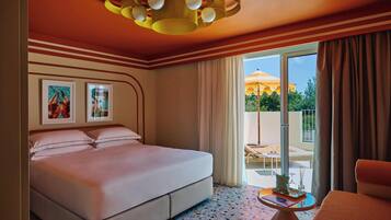 Habitación de hotel con cama, una mesita, una silla, lámpara en el techo y vistas al exterior.