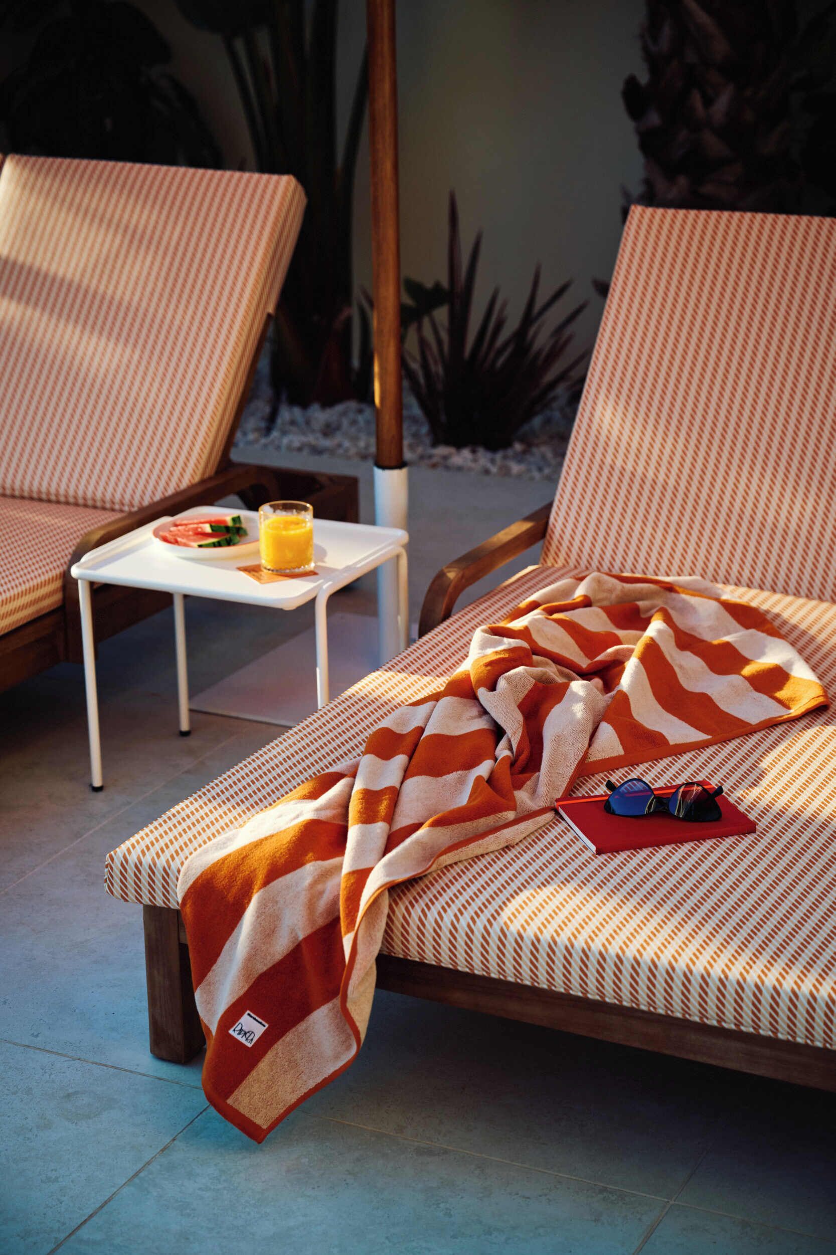A lounge area with two chairs, a small table with a tray, and a blanket on one chair.