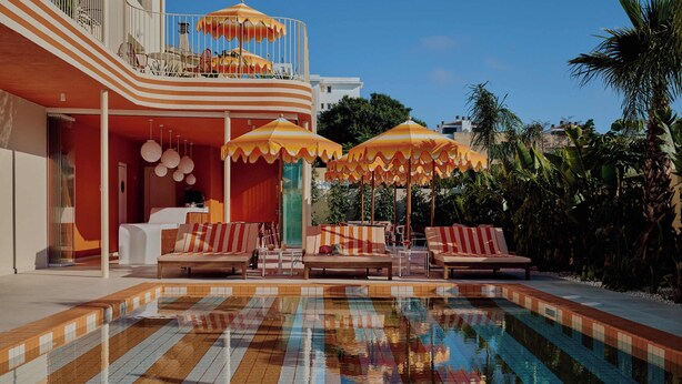 A swimming pool with striped tiles, lounge chairs, and umbrellas. - Riviera Hotel Menorca  (Ciutadella de Menorca)