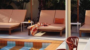 A poolside area with lounge chairs, umbrellas, and a tiled pool.