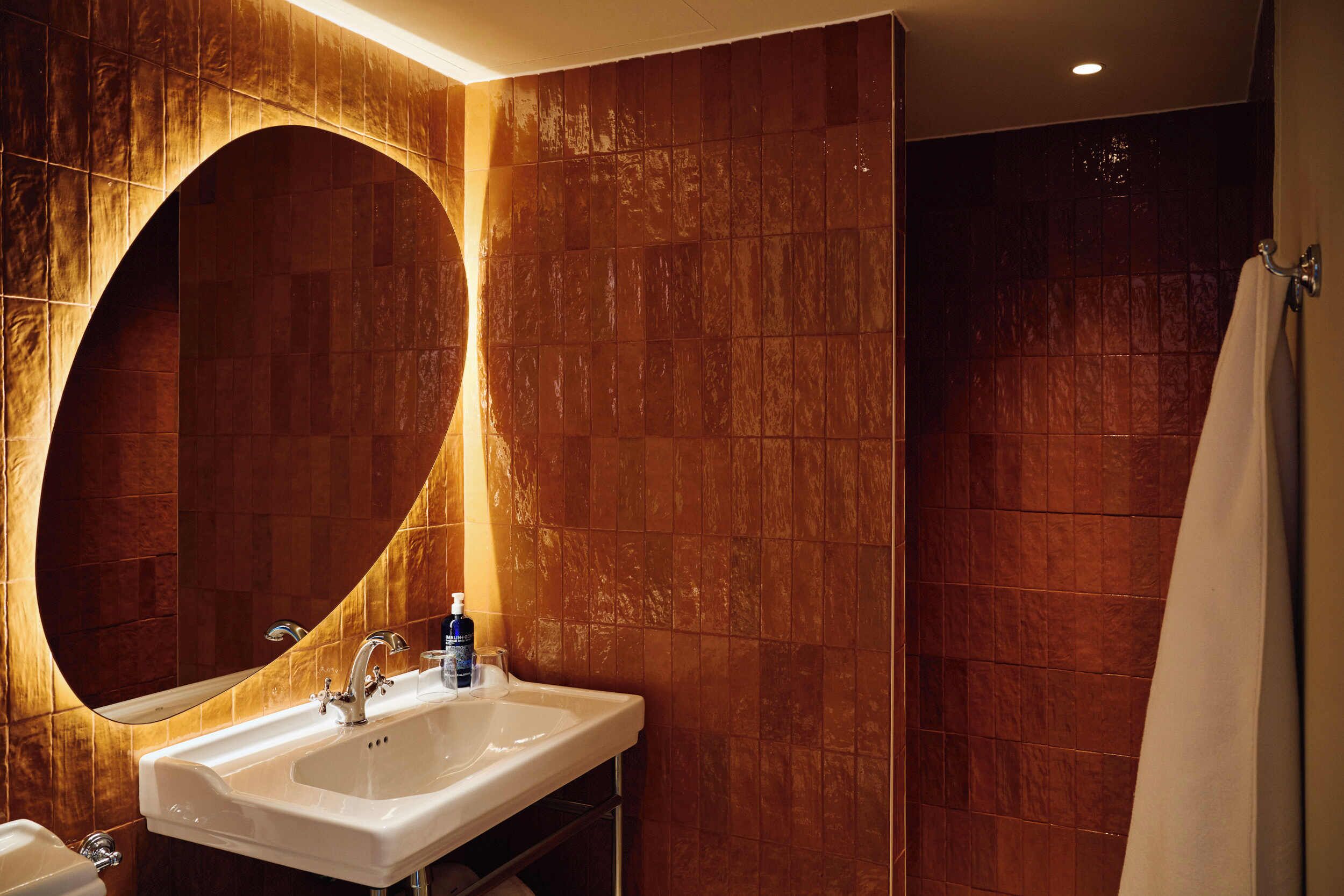 A bathroom with a large mirror, a sink, and a shower.