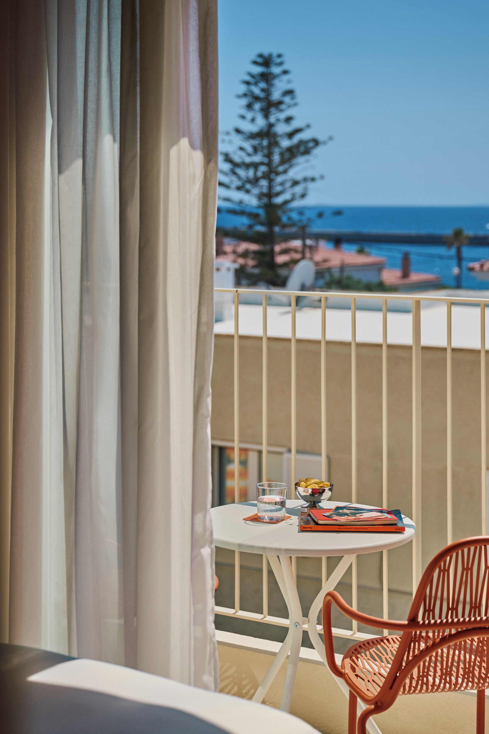 A balcony with a table, a chair, and a view of the ocean.