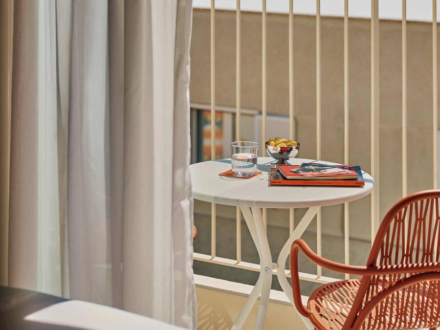 A balcony with a table, a chair, and a view of the ocean.