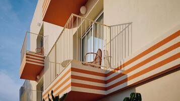 A building with a striped balcony, a chair, and a potted plant.