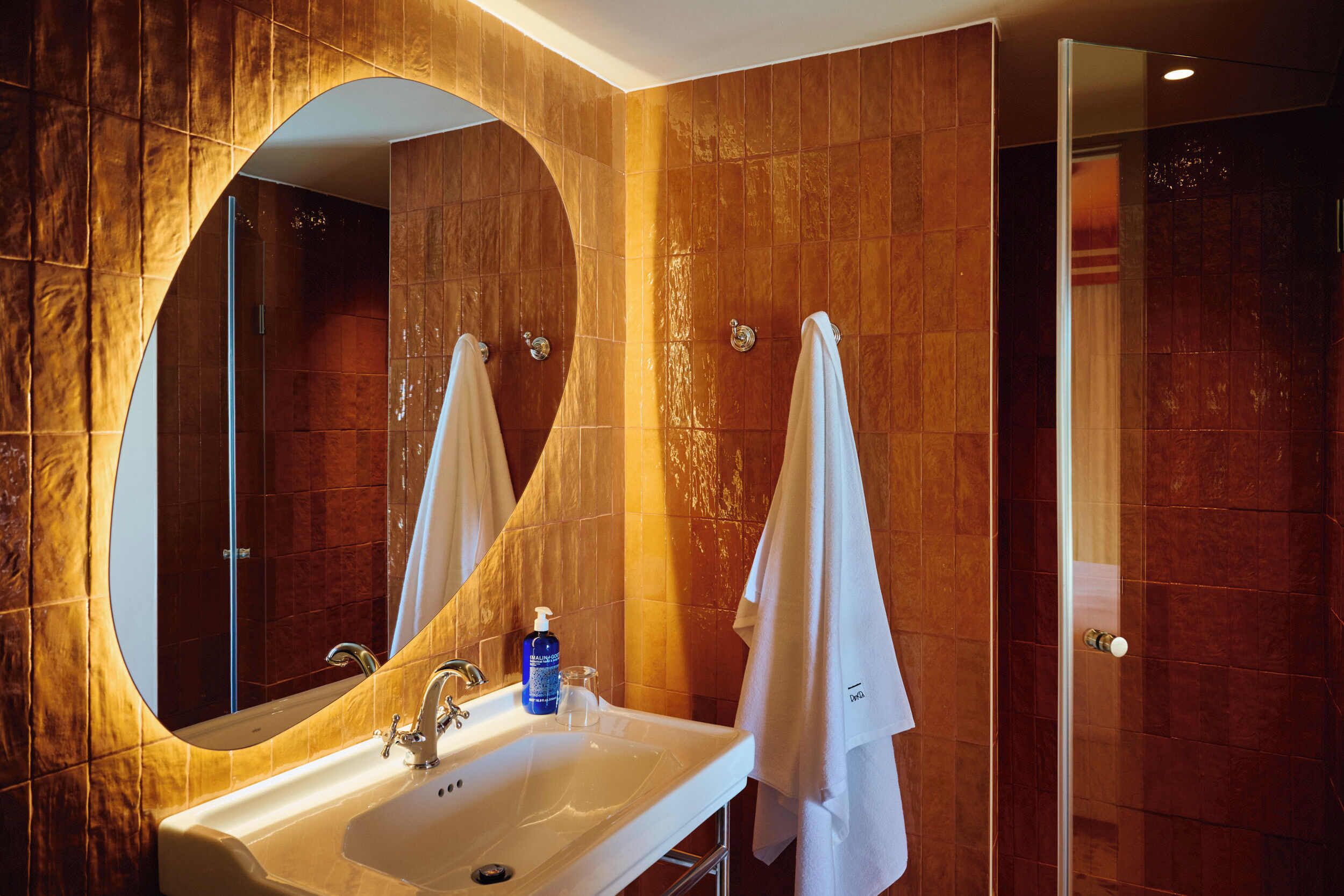 Un baño con un espejo grande, un lavabo y una ducha.
