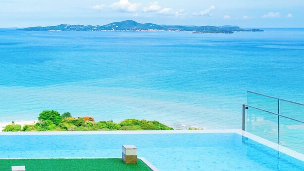 An infinity pool with a clear view of the ocean and distant land. - Sea View High Floor - Breathtaking Views (Pattaya)