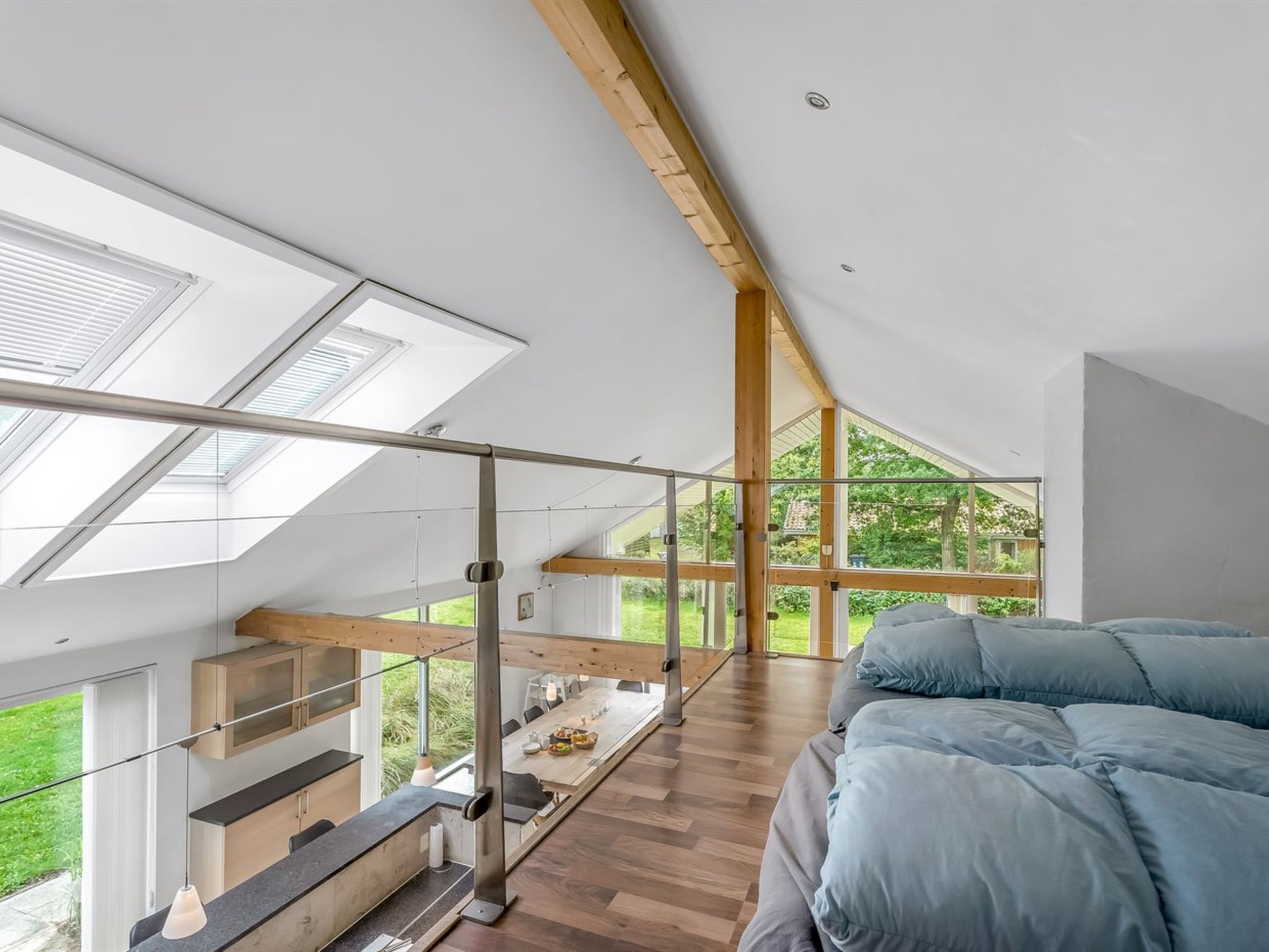 Un dormitorio tipo loft moderno con tragaluces, techo de madera y una cama grande.