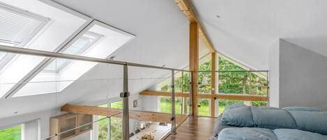 Un dormitorio tipo loft moderno con tragaluces, techo de madera y una cama grande.