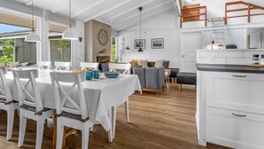 A spacious living area with a dining table, chairs, a sofa, and a kitchen area with cabinets and a countertop.