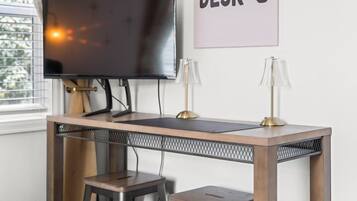 A desk with a television, two lamps, and a sign that reads 'AT THE DESK-O'.