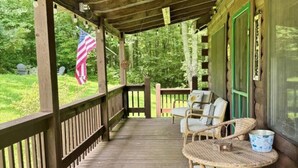 A wooden porch with wicker furniture and an American flag. - Delightful cabin with Fireplace in charming Canvas (Canvas)