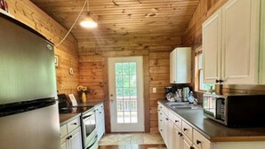 A wooden-paneled kitchen with a refrigerator, stove, microwave, and cabinets. - Delightful cabin with Fireplace in charming Canvas (Canvas)