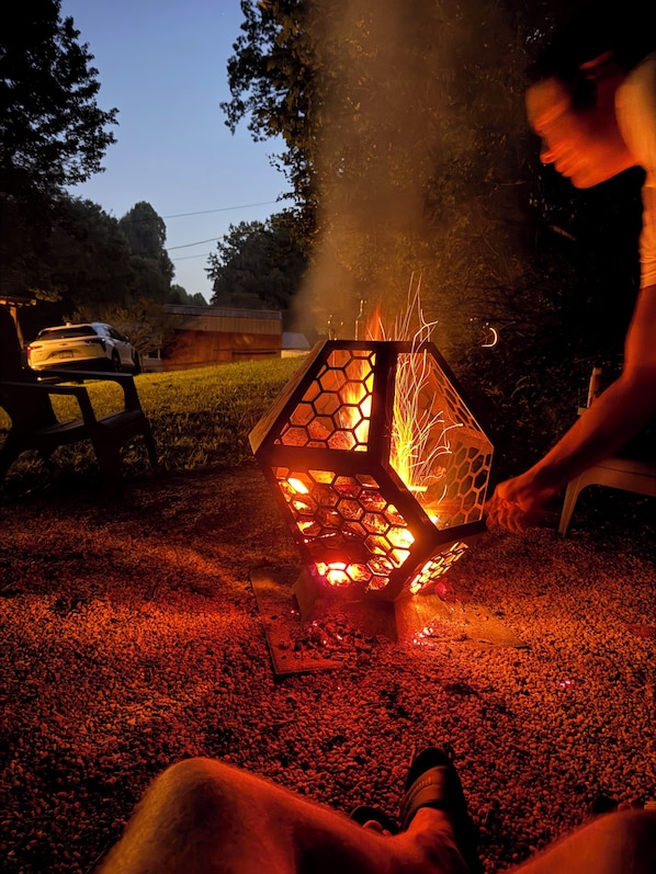 A hexagonal lantern with a fire burning inside, placed on a gravel surface.