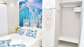 A modern bedroom with a large ocean wave mural, a bed with blue and white bedding, and a macrame wall hanging.