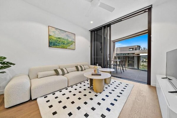 A modern living room with a sofa, coffee table, and a painting on the wall. - Crème de la Crème -Sweet Stay on BNE Casino w Carpark (Brisbane City)