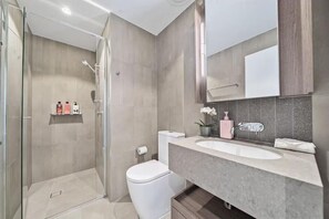 A modern bathroom with a glass-enclosed shower, a white toilet, and a large sink with a mirror above. - Crème de la Crème -Sweet Stay on BNE Casino w Carpark (Brisbane City)