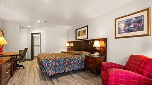 Une chambre d’hôtel avec un lit, un bureau et une chaise, un canapé rouge et un tableau au mur.