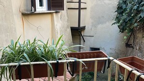 Un balcon doté d’une rambarde en métal, de plantes en pot et d’un petit élément décoratif aquatique.