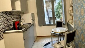 Une cuisine compacte avec un coin repas, une fenêtre donnant sur un espace verdoyant et un tapis à motifs.