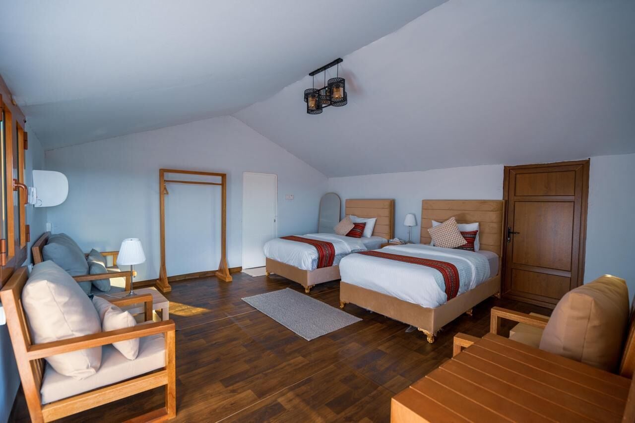 Un dormitorio con dos camas, una silla de madera, un escritorio y un armario.