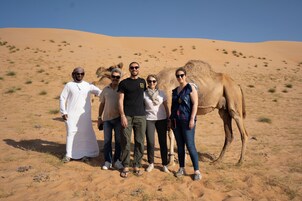 A group of people standing in a desert with sand dunes in the background.