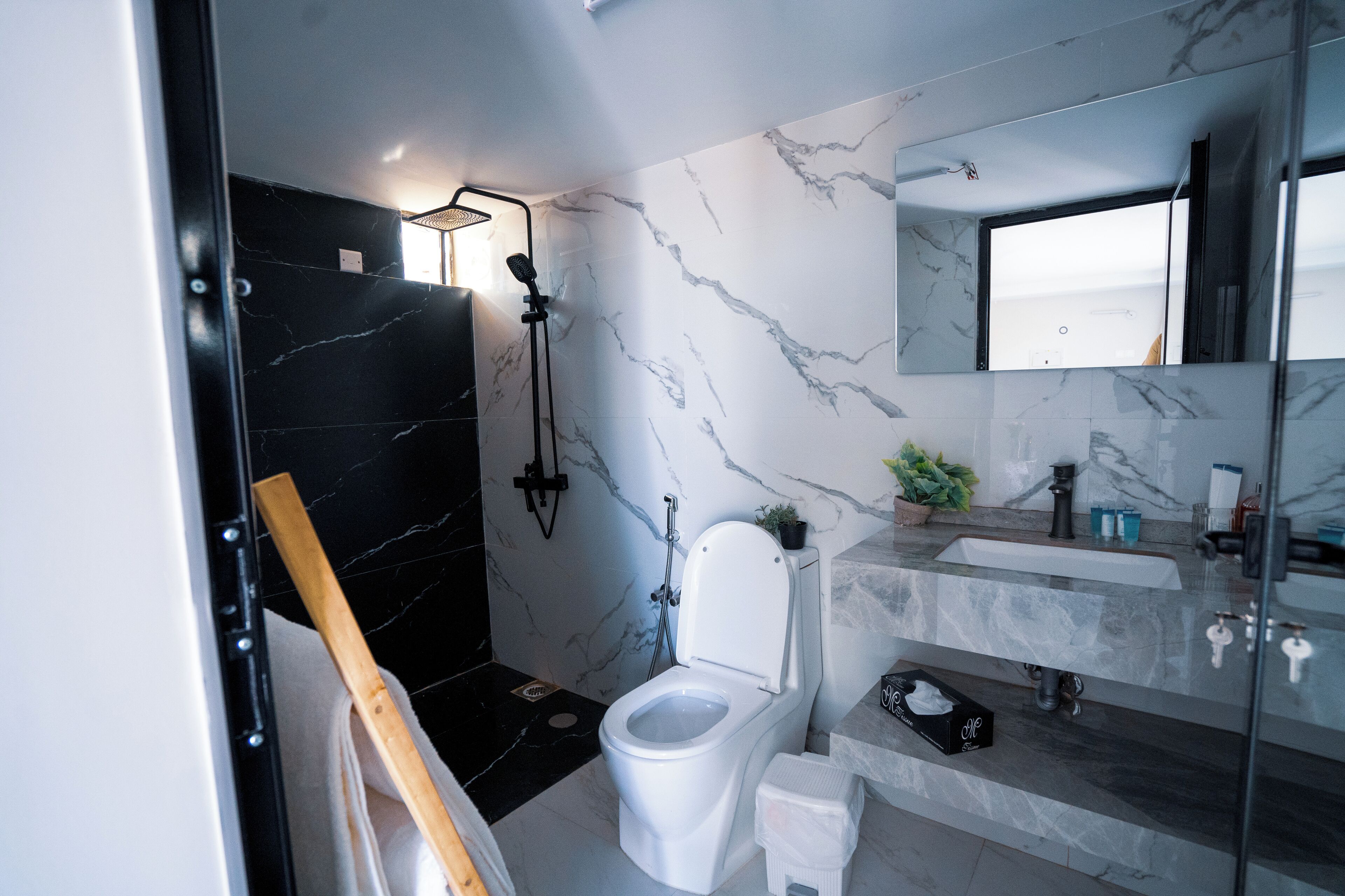 Un baño moderno con lavabo de mármol, inodoro y zona de ducha.