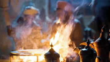 A close-up of a traditional tea set with a teapot and cups, surrounded by smoke from a nearby fire.