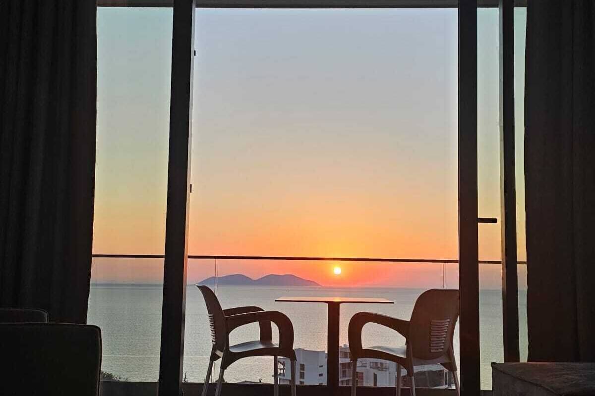 Una habitación con vista al atardecer sobre el mar, con una mesa y dos sillas.