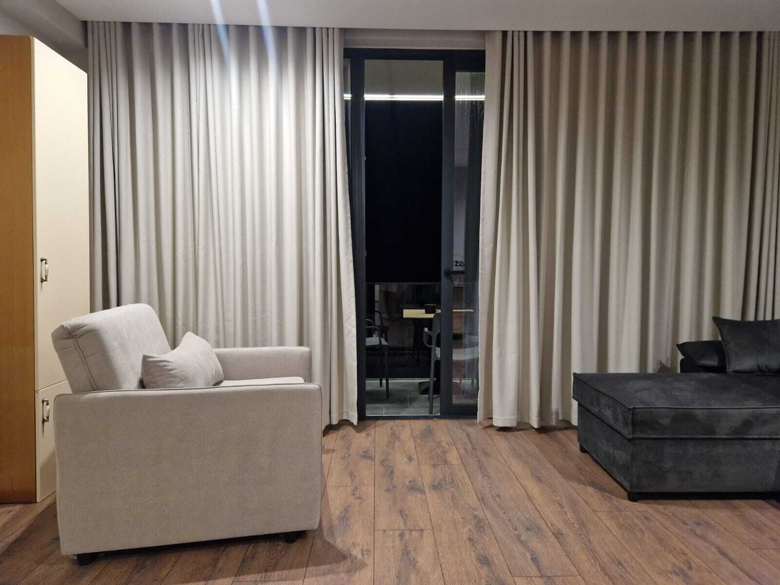 Una sala de estar moderna con un sofá beige, un sofá oscuro y un ventanal de vidrio que da a un balcón.