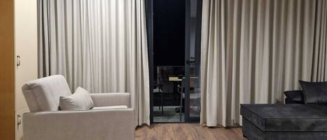 Una sala de estar moderna con un sofá beige, un sofá oscuro y un ventanal de vidrio que da a un balcón.