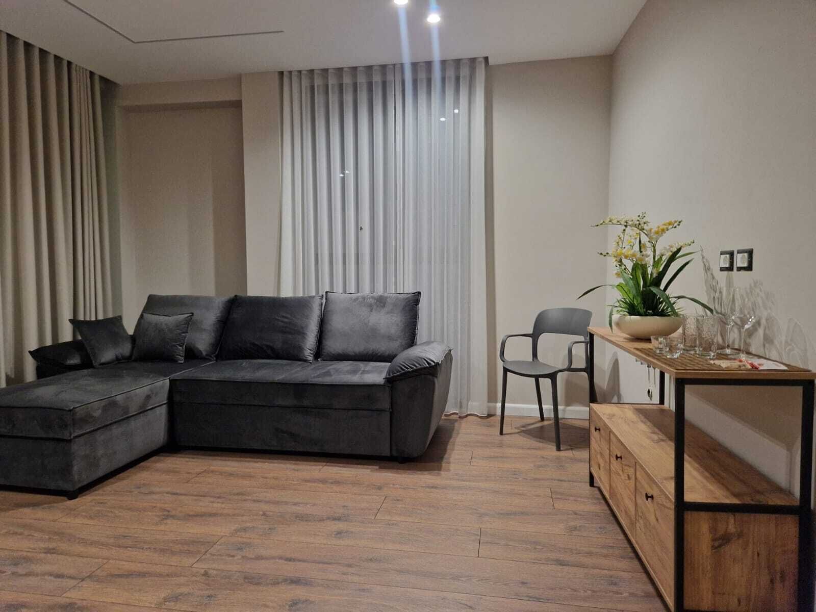 Una sala moderna con un sofá modular, una mesa de centro de madera y una mesita auxiliar con una planta.