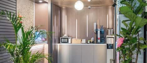 A modern kitchen with a microwave, coffee machine, and a plant.