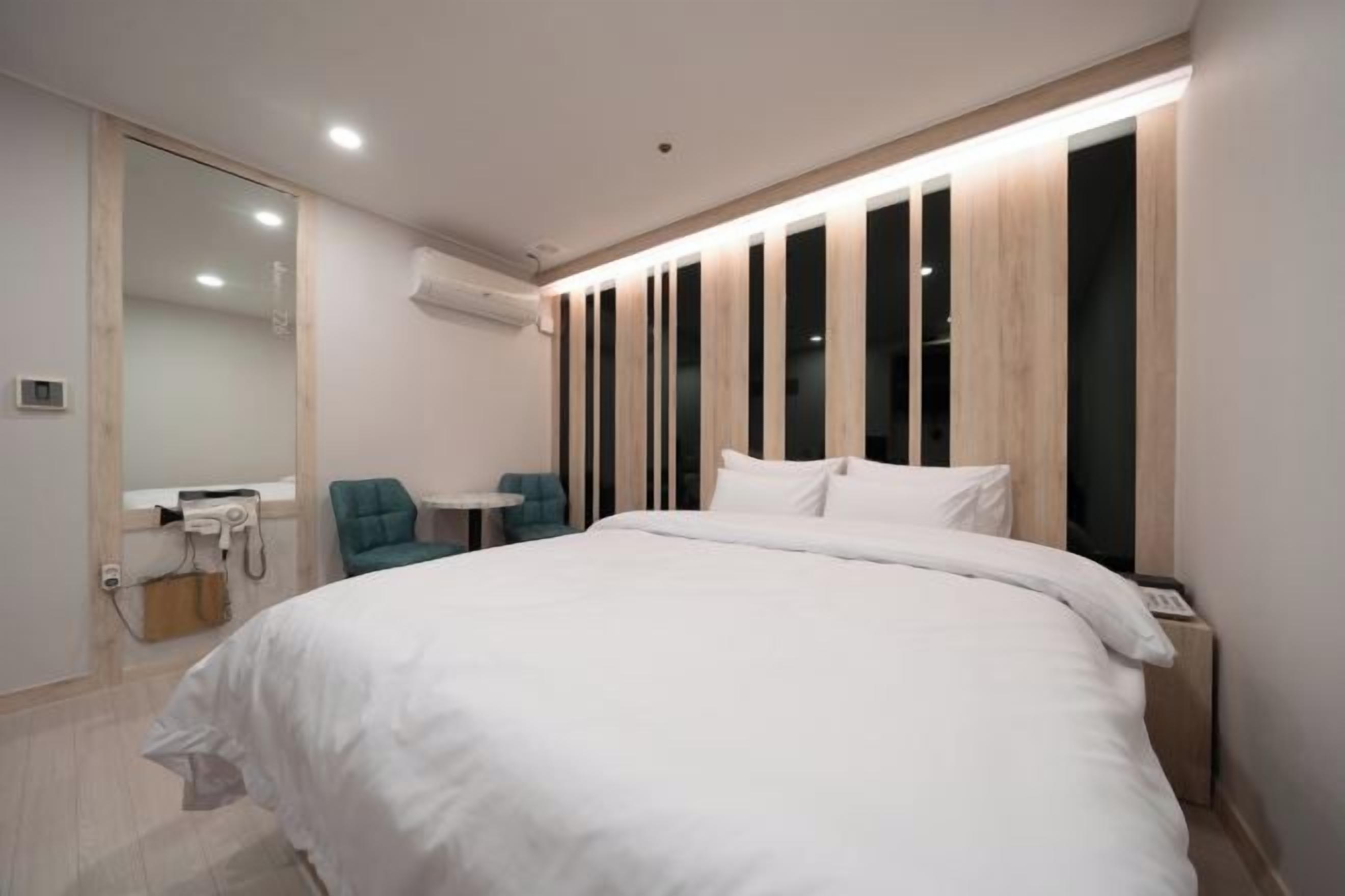 Quarto moderno com uma cama grande, uma pequena escrivaninha e uma cadeira.