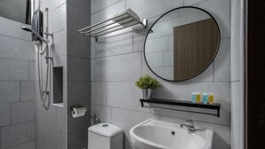 A modern bathroom with a toilet, sink, shower, and a round mirror.