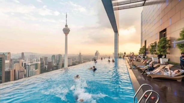 An indoor infinity pool with a city skyline view, including a tower, and lounge areas with sunbeds. - Ritz Residence Platinum KL (Kuala Lumpur)