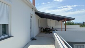 A covered outdoor patio with a table and chairs, a door, and a view of the sky and distant landscape. - Gorgeous apartment in Sukosan with WiFi (Sukosan)