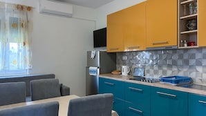 A compact kitchen with a refrigerator, stove, and blue cabinets. There is a dining area with gray chairs and a table. - Gorgeous apartment in Sukosan with WiFi (Sukosan)