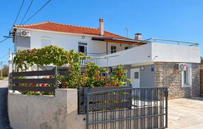 Una casa de dos pisos con techo de tejas rojas, un balcón y una pared de piedra.