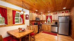 A wooden cabin-style kitchen with a dining table and chairs, a refrigerator, a microwave, and a stove.