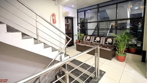 A modern interior with a staircase, a sofa, and large windows. - Hotel Season (Ahmedabad)