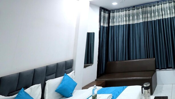 A hotel room with a large bed, a sofa, a small table with toiletries, and a window with curtains. - Hotel Season (Ahmedabad)