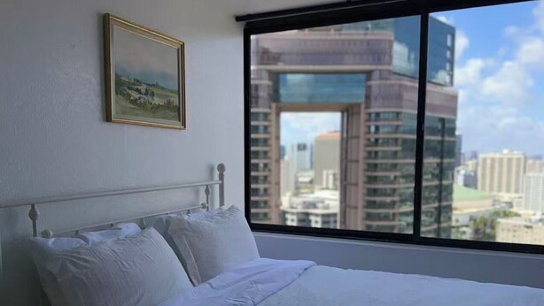 Quarto com uma janela grande, uma cama e um quadro na parede.