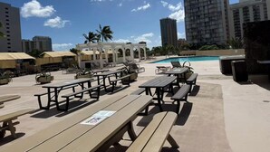 Uma área junto à piscina com mesas de piquenique, guarda-sóis e espreguiçadeiras.