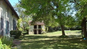 A stone building with a brick chimney, surrounded by a well-maintained lawn and trees.
