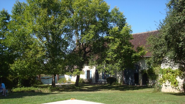 A swimming pool with a clear blue water surface, surrounded by a well-maintained lawn and trees.