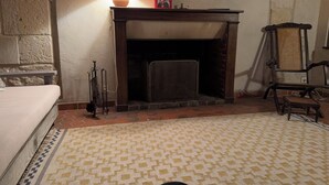 A room with a fireplace, a bed, a patterned rug, and a chair.