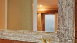 A bathroom with a wooden vanity, a mirror, and two gold-handled soap dispensers. - Koura Jimbaran (Bali)